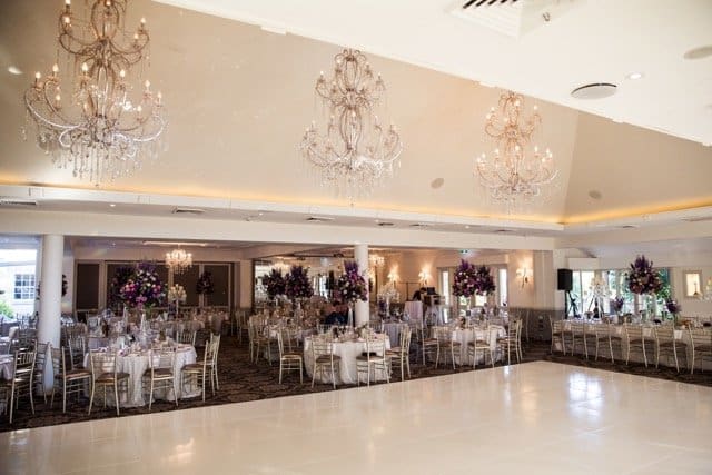 Oatlands house wedding venue showcasing chandeliers and round tables featuring purple florals